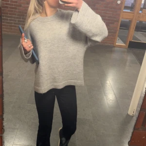 Grå stickad tröja - Säljer en mysig grå stickad tröja med rund hals. Perfekt för kyliga dagar och lätt att matcha med olika outfits. Tröjan har långa ärmar och en avslappnad passform.