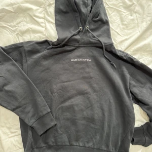 Svart hoodie med tryck - Säljer en svart hoodie med texten 'MAKE ART NOT WAR' på framsidan och ett stort fredsmärke på baksidan. Hoodien har en justerbar huva och långa ärmar med ribbade muddar.