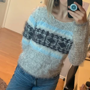 Grå stickad tröja från ONLY - Säljer en mysig grå stickad tröja från ONLY med ett snyggt mönster i blått och svart. Tröjan har långa ärmar och en rund halsringning. Perfekt för kyliga dagar! 💙