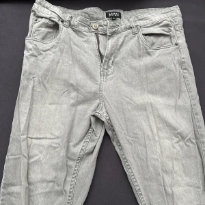 Grå jeansbyxor från MAN - Snygga grå jeans från MAN med klassisk femficksdesign och knappgylf. Perfekta för en clean look.