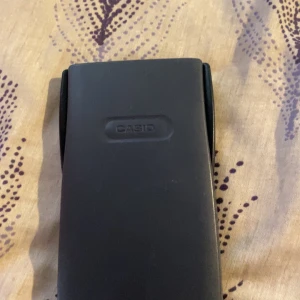 Vetenskaplig kalkylator från Casio - Säljer en vetenskaplig kalkylator från Casio, modell fx-82MS. Den har en skyddande grå hölje och erbjuder funktioner som S-V.P.A.M. och standardavvikelseberäkningar. Perfekt för studier i matematik och naturvetenskap. Inkluderar snabbreferensguide på baksidan av höljet.