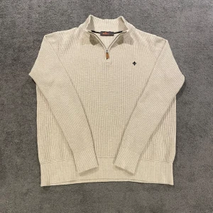 Beige stickad half zip från Morris - Säljer en stilren beige stickad half zip från Morris med dragkedja vid halsen och ett diskret broderat emblem på bröstet. Nypris:1800kr vs mitt pris:599kr Plagget är som helt nytt och har inga skador någonstans. Det är bara att skriva ifall du har några funderingar priset är inte hugget i sten🤩✅