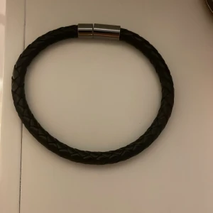 Svart flätat armband  - Snyggt svart flätat armband med ett stilrent magnetlås i silverfärg. Perfekt accessoar för en stilren look. Passar både till vardag och fest. Säljer detta pga det är för litet. Köpt från kidsbrandstore för 149kr mitt pris 50kr! Skriv om ni har funderingar.