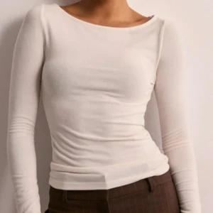 Vit långärmad topp - Säljer en stilren vit långärmad topp med en tight passform och utsvängda ärmar. Perfekt för en minimalistisk look. Toppen är enkel och elegant, vilket gör den lätt att matcha med olika outfits.