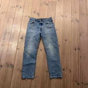 Levi's 501 jeans - Klassiska Levi's 501 jeans i en ljusblå tvätt. De har en rak passform och är tillverkade i slitstarkt denim. Byxorna har fem fickor och knappgylf. Perfekta för en avslappnad stil.