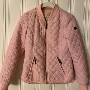 Rosa quiltad jacka från Z-Ip - Säljer en snygg rosa quiltad jacka från Z-Ip. Jackan har en dragkedja framtill och två fickor med dragkedjor. Den är långärmad och har en bekväm passform. Perfekt för vår och höst! Storlek 36/38. 100 kronor plus frakt 