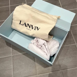 Lanvin skor - Snygga svarta sneakers från Lanvin med glansig finish och vita sulor. Skorna har snörning och en rund tå, vilket ger en stilren look. Perfekta för en trendig och elegant stil, storlek 42