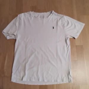 Vit t-shirt från Polo Ralph Lauren - Säljer en klassisk vit t-shirt från Ralph Lauren med en liten broderad logga på bröstet. T-shirten har en normal passform och är kortärmad, perfekt för en avslappnad stil.