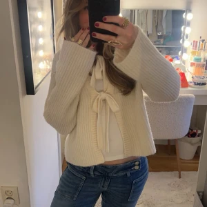 Vit stickad kofta med knyt/rosetter - Säljer en mysig vit stickad kofta med knyt framtill. Koftan har långa ärmar och en ribbad struktur som ger en stilren look. Perfekt för kyliga dagar! Jätte mysigt material och är super gullig!🌸Pris kan diskuteras 