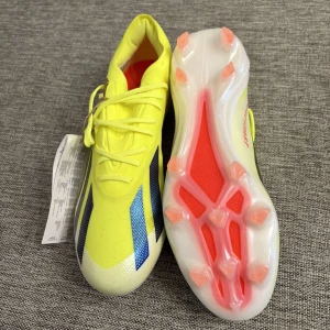 fotbollsskor från Adidas - Säljer ett par Adidas X Crazyfast Elite F fotbollsskor i en lysande gul färg med blå detaljer. Skorna har snörning och en lätt syntetisk ovandel för optimal hastighet och kontroll på planen. Perfekta för spelare som vill ha en snabb och smidig känsla. Storlek 41