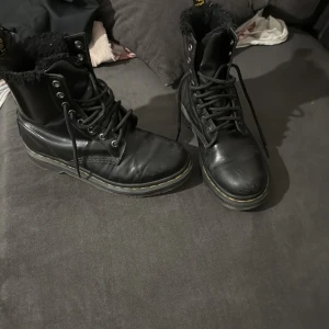 Dr. Martens svarta vinter boots  - Svarta boots i skinn med snörning och foder. Perfekta för vintern då de är fodrade. Användna, men i ganska bra skick. Lite slitna fast inget som märks speciellt mycket. 