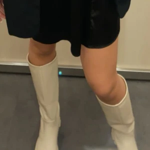 Beige stövlar med grov sula - Snygga beige stövlar med en robust och grov sula. Perfekta för att ge en stilren touch till din outfit. De är höga och har en klassisk design som passar till många tillfällen.