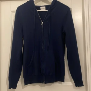 Kashmir hoodie från John Henric -   Mörkblå hoodie från John Henric i mjuk kashmir. Tröjan har dragkedja och huva med snörning, Ny pris 2499, Mitt pris 1200