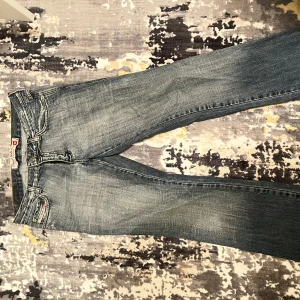 Blå lågmidjade jeans från Diesel - Säljer ett par snygga lågmidjade blåa jeans från Diesel. De har en klassisk femficksdesign och en cool tvättad look. Perfekta för en avslappnad stil. Tillverkade i Italien. Så populära och snygga!! Passar mig som bär S och m på jeans. Storlek 36 bär jag oftast men även 38. Dom är lite slitna där nere men det märks inte så.