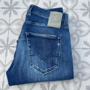 Blåa Replay Grover jeans - Säljer ett par snygga blå Replay Hyperflex Grover jeans i extremt bra skick! De har en slim fit passform och är tillverkade i ett stretchigt material för extra komfort. Klassisk femficksdesign med märkets logga på bakfickan och en diskret Replay-detalj vid fickan fram. Storlek 30/32. Hör av dig vid det minsta lilla! 🤙🙌