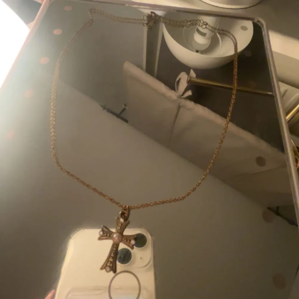 Elegant halsband med ett korsformat hänge dekorerat med en pärla i mitten. Kedjan är tunn och smidig, vilket ger ett stilrent intryck. Perfekt för att lägga till en subtil touch av elegans till din outfit. Ordinarie pris 89kr. 🩷. Asusteet.