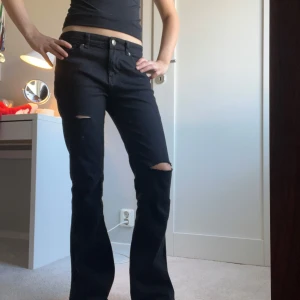 Svarta jeans med slitningar - Snygga svarta jeans med slitningar på knäna. De har en klassisk femficksdesign och knappar i midjan. Perfekta för en avslappnad stil. Pris kan diskuteras