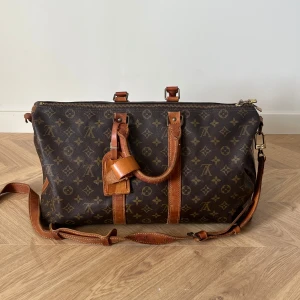 Louis Vuitton kepall 45 - En vintage Louis Vuitton Kepall 45. Axelremen har gått av men går säkert att laga. Annars kan man ha utan remmen. Väskan är köpt på auktion på Bukowskis för 2 år sedan för 12 000kr. Har verifikation på det om det önskas. 