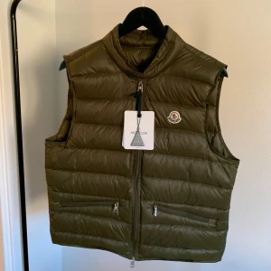 Moncler GUI väst - Moncler väst i storlek L men är väldigt liten i storlek. Helt ny, aldrig använd. Skriv för mått eller annat!