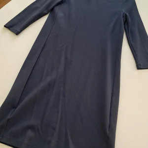 Mörkblå klänning från Part Two - Snygg mörkblå klänning från Part Two i en blandning av viskos, polyamid och elastan. Klänningen har en enkel design med långa ärmar och en rak passform. Perfekt för en stilren look.