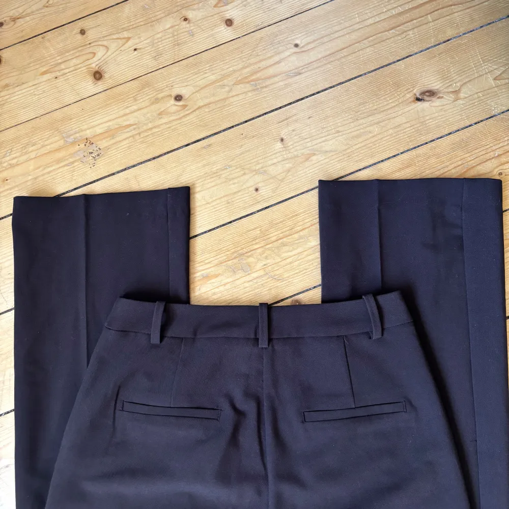 Snygga mörkbruna kostymbyxor med hög midja och raka ben. Byxorna har en klassisk design med hällor för bälte och diskreta bakfickor. Perfekta för en stilren look. Endast använda 1 gång. Nypris 600:-. Farkut & Housut.