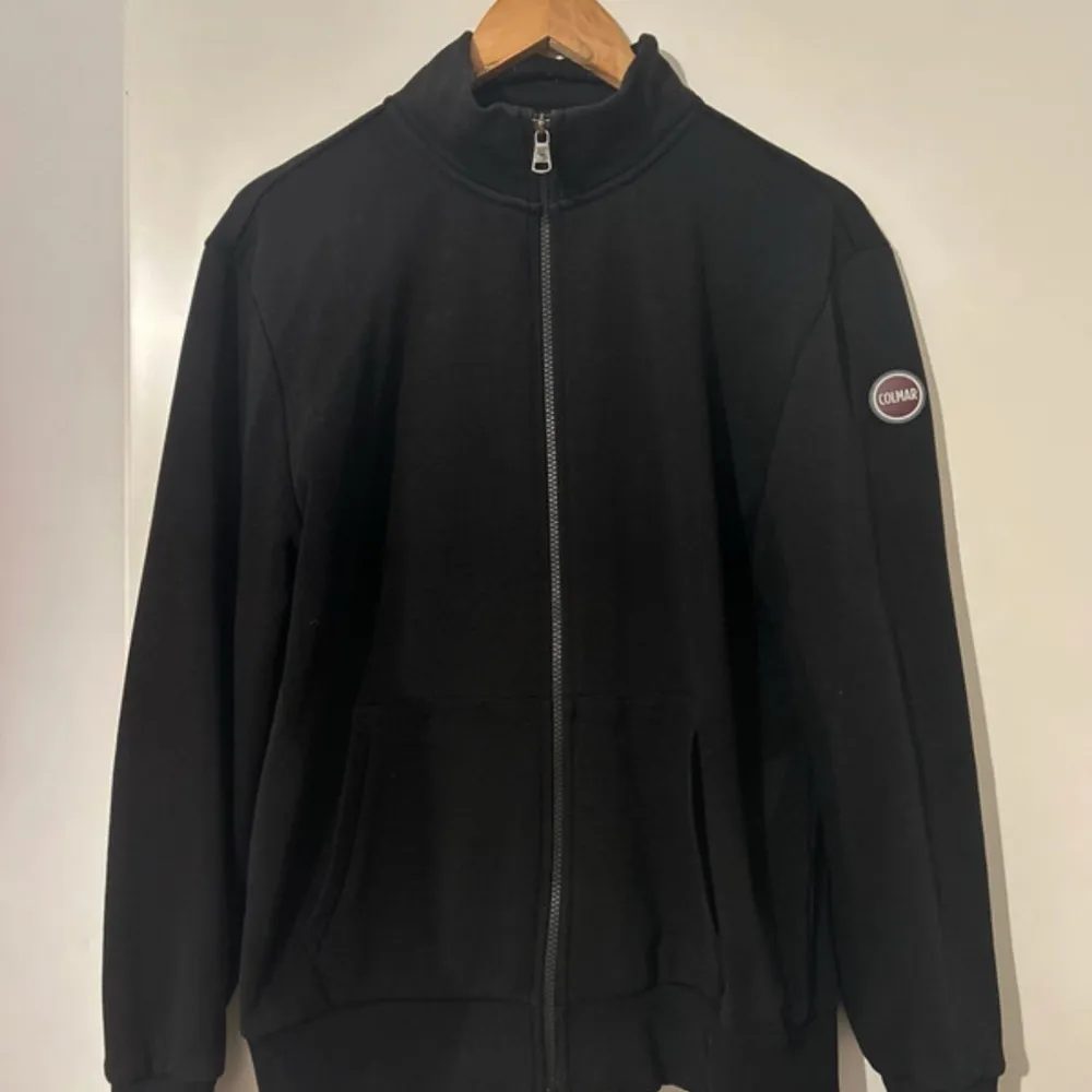 Snygg svart fullzip från Colmar. Perfekt för en stilren look. Passar bra till både vardag och mer avslappnade tillfällen. Kan gå ner i pris vid snabb affär. Neuletakit & Villapaidat.
