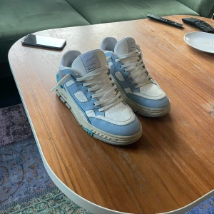 Blå och vita sneakers från Axel Arigato - Snygga sneakers i blått och vitt från Axel Arigato. Skorna har en modern design med snörning och en bekväm passform. Perfekta för en stilren look. Skorna är använda i några få dagar och i nästan ny skick. Original Dustbag och box ingår. Ny pris 3150kr.
