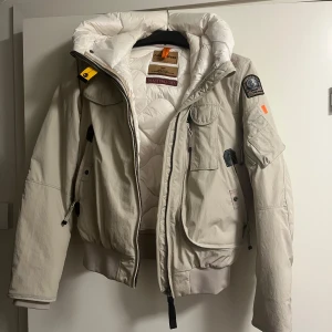 Beige jacka från Parajumpers - Säljer en snygg beige jacka från Parajumpers med luva och flera praktiska fickor.