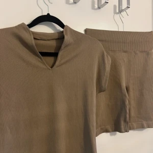 Träningsset  - Brunt ribbat träningsset med en v ringad tröja och shorts i lår längd. 