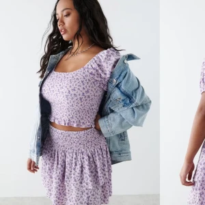Lila blommig kortkjol - Charmig lila kortkjol med blommigt mönster och volangdetaljer. Perfekt för en somrig look. Den elastiska midjan ger en bekväm passform.
