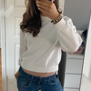 Vit croppad sweatshirt - Säljer en stilren vit croppad sweatshirt med långa ärmar. Perfekt för en avslappnad look. Passar bra till jeans eller kjol. Storlek xs. Hör av dig vid intresse! Pris kan diskuteras 