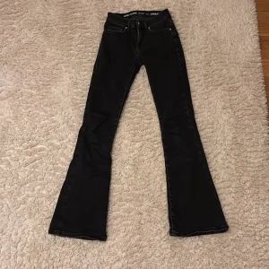 Svarta flare jeans från bikbok - Snygga svarta flare jeans från bikbok med låg midja. De har en klassisk femficksdesign och stängs med dragkedja och knapp. Perfekta för en trendig look. Använda fåtal gånger.