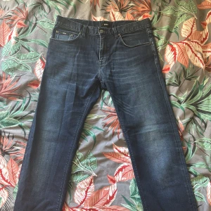 Mörkblå jeans från Hugo Boss - Snygga mörkblå jeans från Hugo Boss med en klassisk femficksdesign. De har en stretchig passform för extra komfort och en stilren look. Perfekta för en avslappnad men ändå stilfull outfit. Storlek 33/34