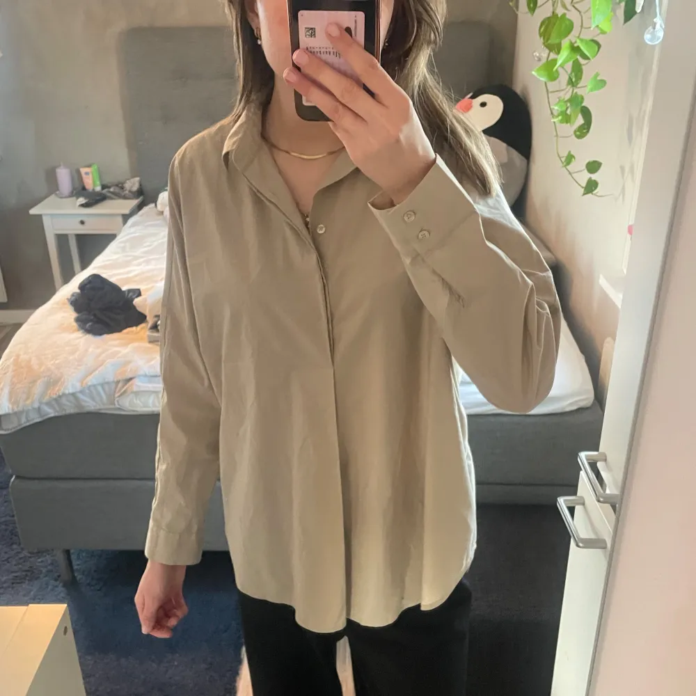 Snygg beige skjorta med långa ärmar och klassisk krage. Perfekt för en stilren look. Skjortan har en avslappnad passform och knappar framtill.. Paidat.