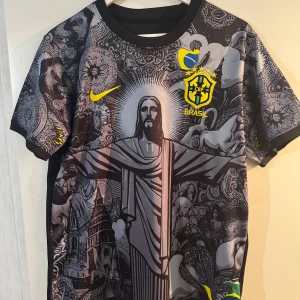 Svart Brasilien fotbollströja med Neymar Jr. Storlek L fast liten, så M passar också. - Snygg svart fotbollströja från Nike med Brasilien-tema. Tröjan har ett unikt mönster med Kristusstatyn och djurmotiv. Neymar Jr och nummer 10 pryder baksidan i gult. Perfekt för fans av det brasilianska landslaget!