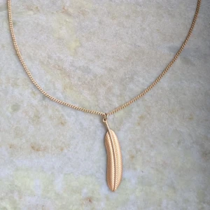 Halsband med fjäderberlock från Claire's - Elegant halsband från Claire's med en vacker fjäderberlock. Kedjan är tunn och justerbar med en karbinhake för enkel användning. Perfekt för att lägga till en subtil touch av stil till din outfit.