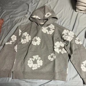 Demin Tears  - Säljer en grå hoodie med ett unikt mönster av vita blommor. Den har en bekväm passform och en klassisk huva. Perfekt för en avslappnad stil.