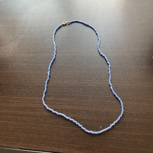 Blått pärlhalsband - Snyggt blått pärlhalsband med små, jämna pärlor och ett guldfärgat lås. 