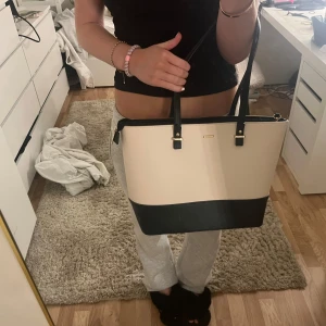 Beige och svart handväska från H&M (tror jag)  - Snygg handväska i beige och svart frpn H&M (tror jag, är inte säker !). Väskan har en praktisk dragkedja och är perfekt för att bära dina dagliga nödvändigheter. Den stilrena designen gör den lätt att matcha med olika outfits. Otroligt rymlig och snygg! 