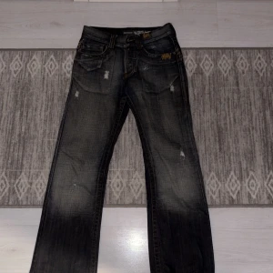 Blåa jeans från Smog - Snygga blåa jeans från Smog med slitna detaljer och kontrastsömmar. De har en klassisk femficksdesign och knappar i gylfen. Perfekta för en avslappnad stil.