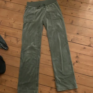 Gröna mjukisbyxor från Juicy Couture - Säljer ett par gröna mjukisbyxor från Juicy Couture. Byxorna har en bred resårmidja med snörning och stora fickor fram. Baktill finns två fickor med knappar. Perfekta för en avslappnad stil. Gör en liten intresse koll för ör väldigt osäker om jag vill sälja