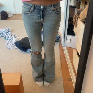 Blå bootcut jeans från weekday - Snygga blå bootcut jeans med egengjort hål. Storlek 25/32