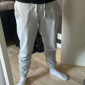 Grå mjukisbyxor med snörning - Säljer ett par bekväma grå mjukisbyxor med snörning i midjan. Perfekta för en avslappnad dag hemma eller en snabb tur till affären. Byxorna har en normal passform och är tillverkade i mjukt material för extra komfort.