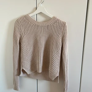 Beige stickad tröja - Säljer en stilren beige stickad tröja med rund hals och långa ärmar. Perfekt för kyligare dagar och enkel att matcha med olika outfits. Tröjan har en ribbad struktur som ger en fin textur och extra värme.