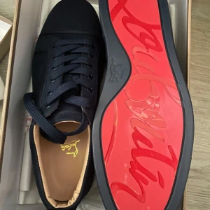 Svarta sneakers från Christian Louboutin - Snygga svarta sneakers från Christian Louboutin med den ikoniska röda sulan. Skorna har snörning och en stilren design som passar perfekt för en trendig look.