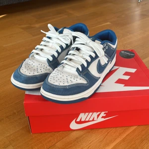 Nike Dunk i blått och vitt - Snygga Nike Dunk sneakers i en fräsch kombination av blått och vitt. Skorna har en klassisk design med snörning och en bekväm passform. Perfekta för en stilren look. Nypris ligger runt 2800kr. 