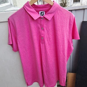 Rosa pikétröja från FootJoy - Rosa pikétröja från FootJoy. Tröjan har en klassisk krage och tre knappar framtill. Perfekt för golf. Nypris 799