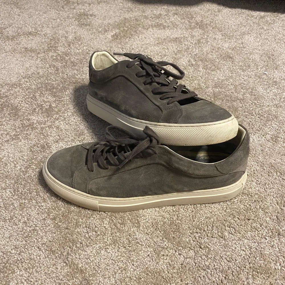 Snygga grå sneakers i mocka med snörning och vit sula. Perfekta för en stilren och avslappnad look. Passar bra till både jeans och chinos.. Kengät.