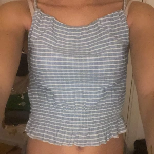 Blåvit topp - Säljer en söt blå- och vitrandig linnetopp, med korsade band i ryggen!