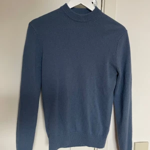 Blå stickad tröja från MNG (mango) - Säljer en stilren blå stickad tröja från MNG, (mango) tillverkad av italienskt garn. Tröjan har en klassisk design med långa ärmar och ribbade kanter vid hals, ärmslut och nederkant. Vid minsta fundering eller prisförslag kontakta mig💭